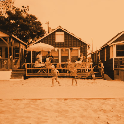 Vintage photo of a family barbecuing on the porch of a sandy bungalow