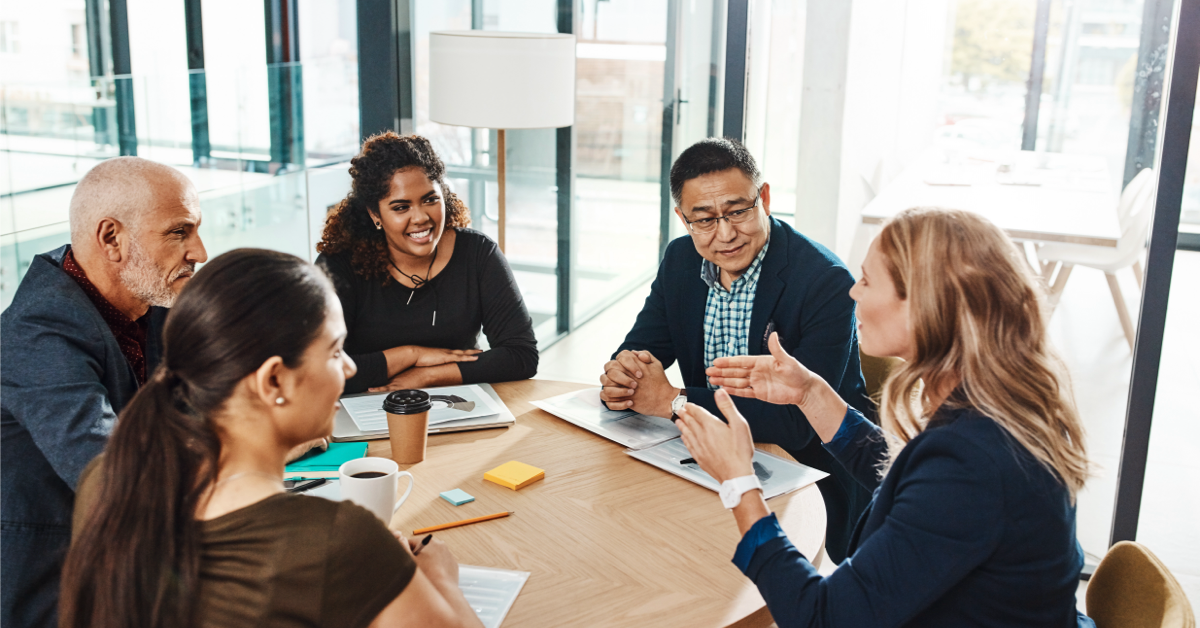 Cross-departmental team sitting together at a meeting