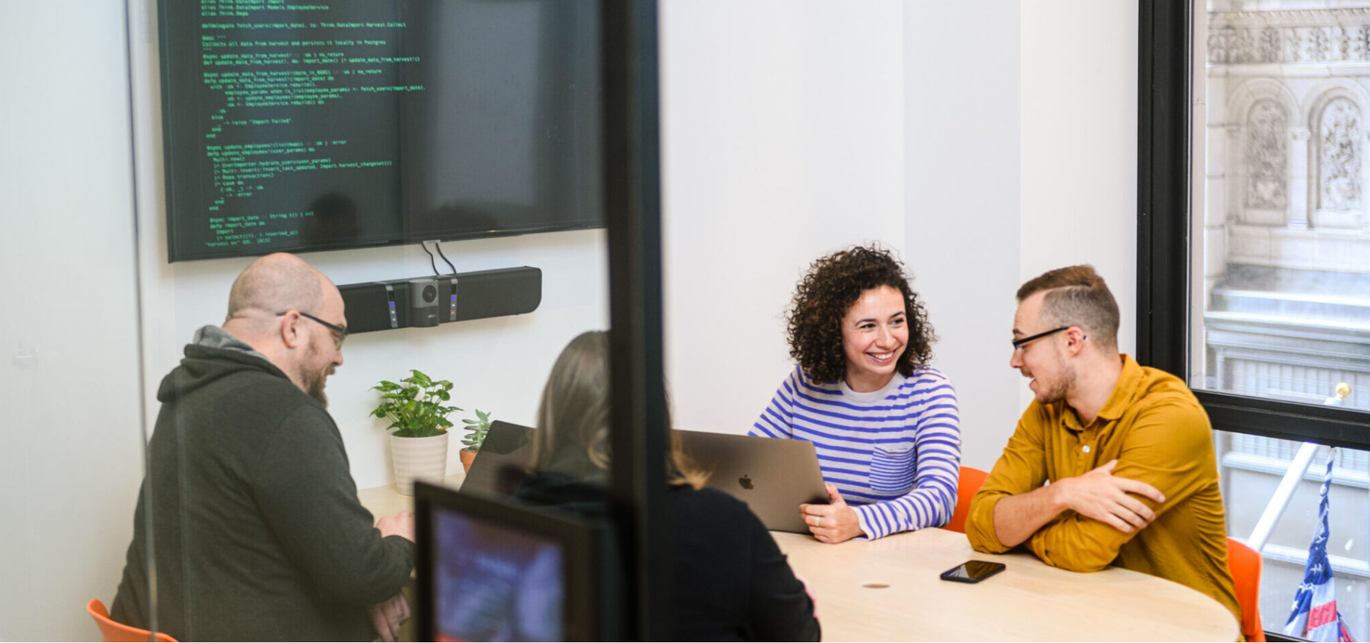 Four people collaborating near a screen with code