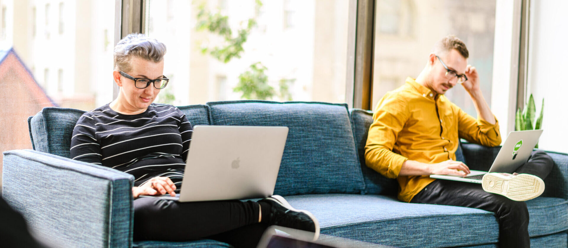 two people working on their laptops sitting on a couch