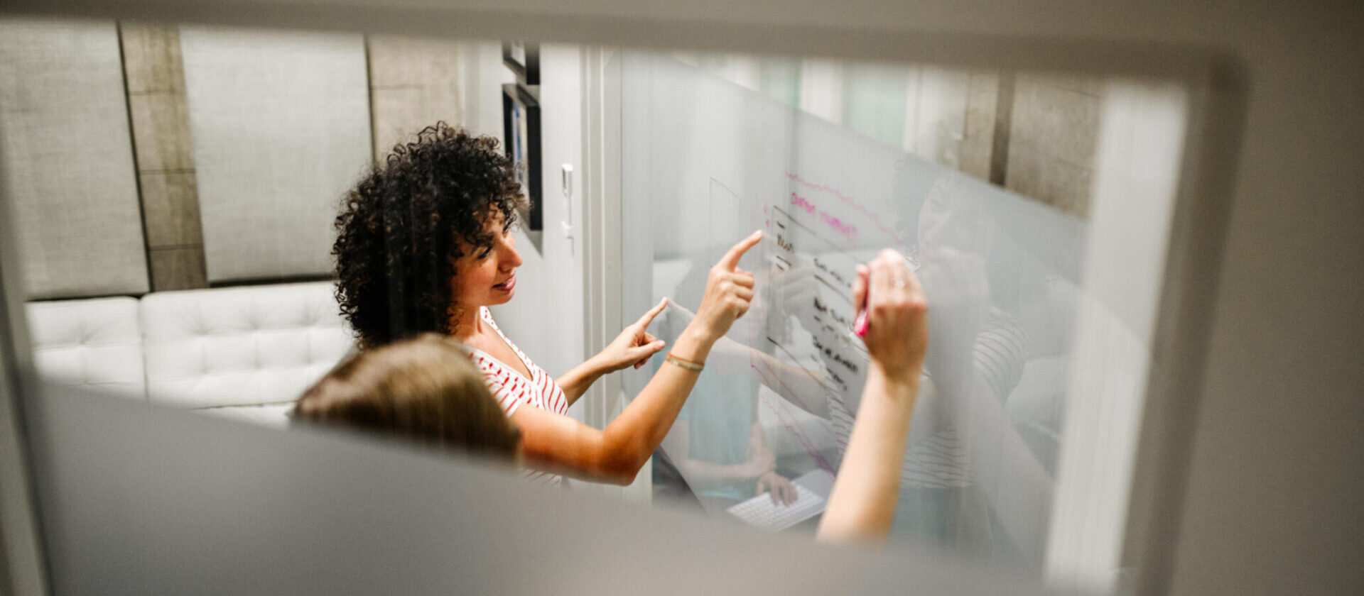 people writing together on a glass wall