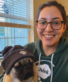 person holding a pug wearing a beanie