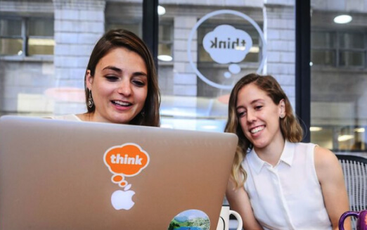 two people smiling and working on a laptop