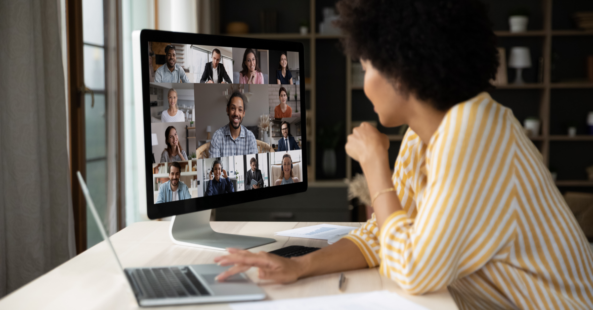 Woman working at her computer and on a zoom call with multiple coworkers