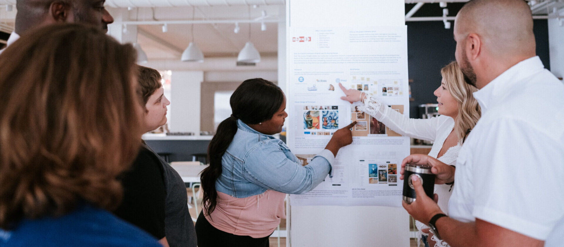A group of people collaborating in front of print out of a project with screens
