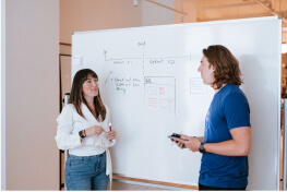 Two people having a conversation and brainstorming on a whiteboard