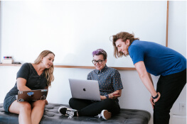 A group of people discussing a project looking at a laptop