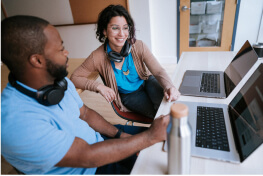 Two people sitting at laptops talking