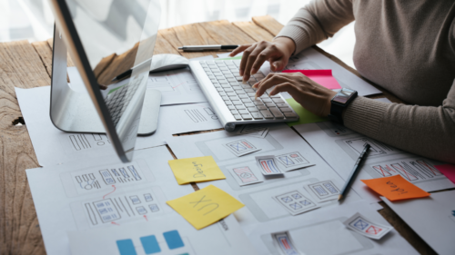 A UX writer working at a computer with UX wireframes