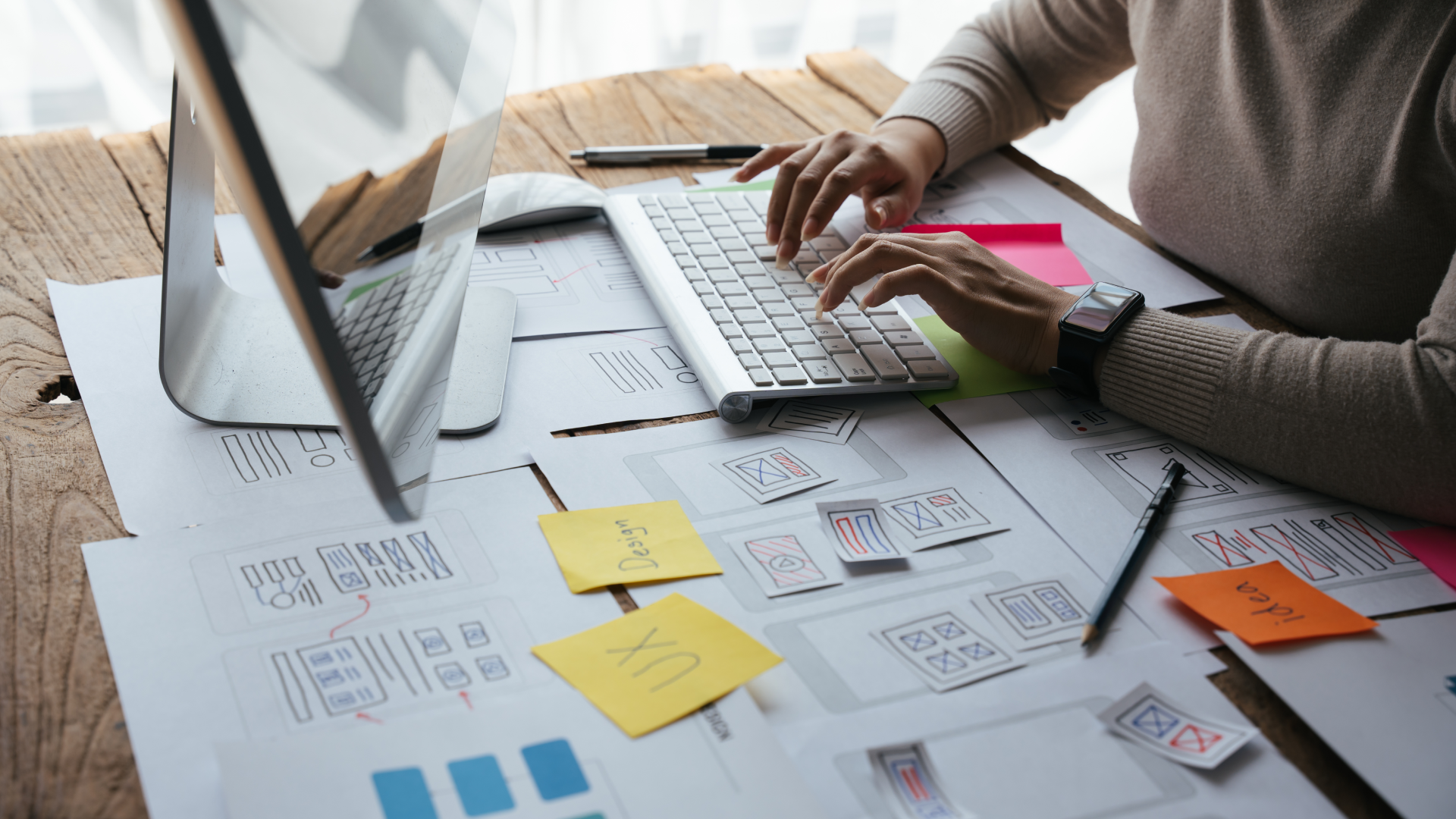 A UX writer working at a computer with UX wireframes