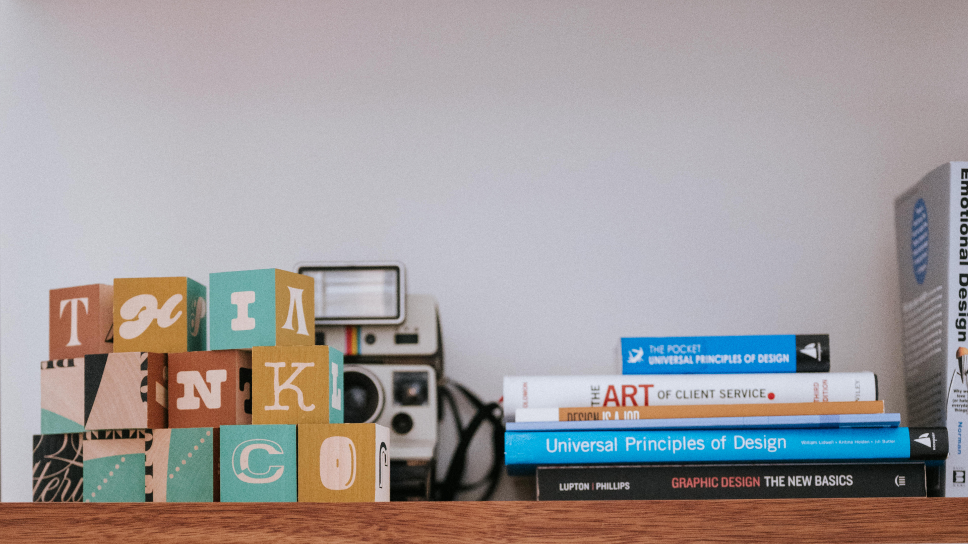 Bookshelf with blocks spelling Think Co, a camera, and design books